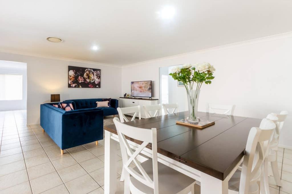 sala de estar con mesa y sofá azul en Executive and Family Home Large - Flinders View 24, en Ipswich