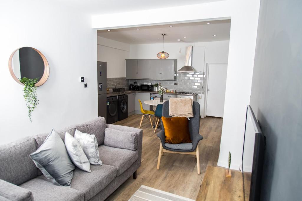 a living room with a couch and a kitchen at The Kensington House - Contemporary Accommodation in Nottingham in Nottingham