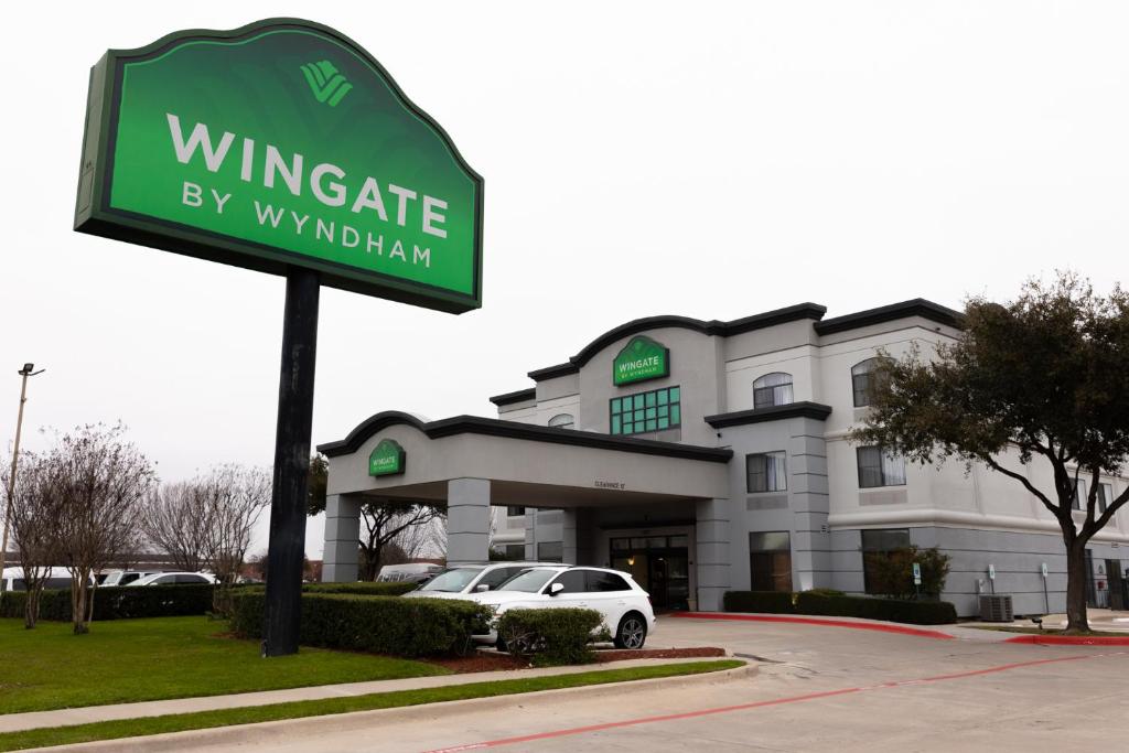 a sign in front of a building with a car at Wingate by Wyndham - DFW North in Irving