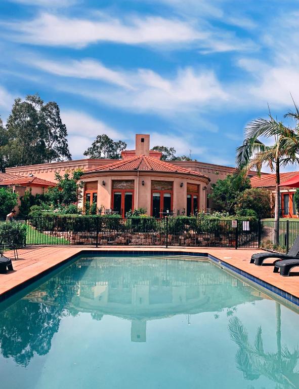 a house with a swimming pool in front of a building at Estate Tuscany in Pokolbin