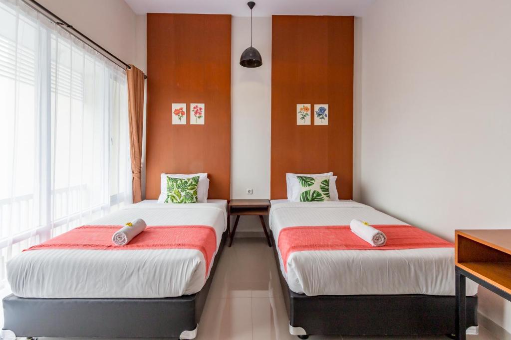 Habitación con 2 camas y sábanas rojas y blancas. en Omah Manis en Yogyakarta
