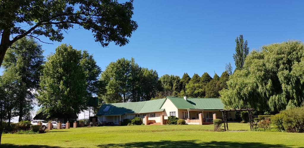 a house with a green roof on a grass field at Pennygum Country Cottages in Underberg