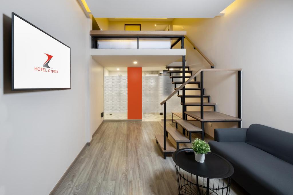 A narrow contemporary lounge with a sofa, coffee table and open staircase.