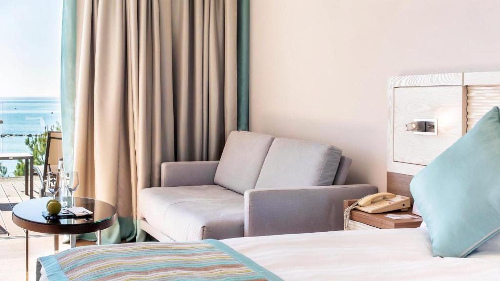 a bedroom with a bed and a couch and a chair at Crowne Plaza Limassol by IHG in Limassol