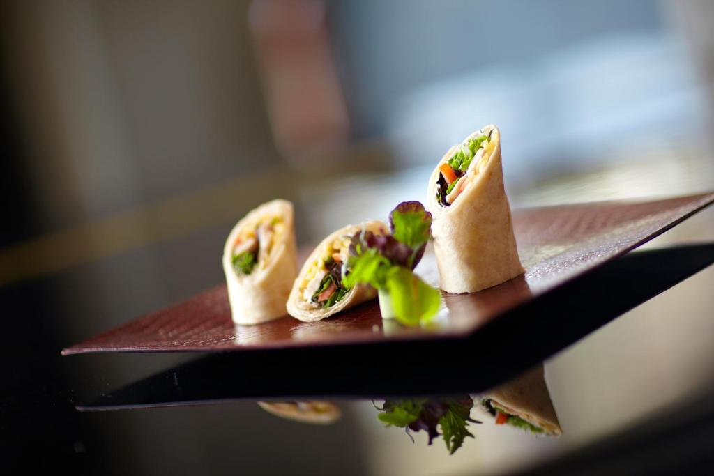 three hot dogs on a plate on a table at Crowne Plaza Limassol by IHG in Limassol