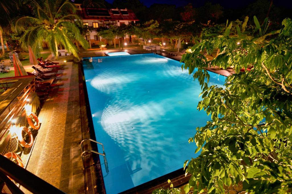 a swimming pool at night with palm trees and chairs at Hotel 4 U Saliya Garden in Anuradhapura