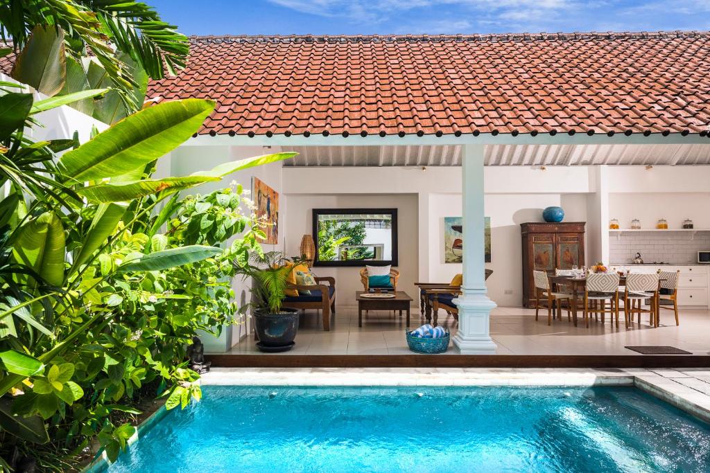 a villa with a swimming pool in front of a house at Villa Atma in Seminyak