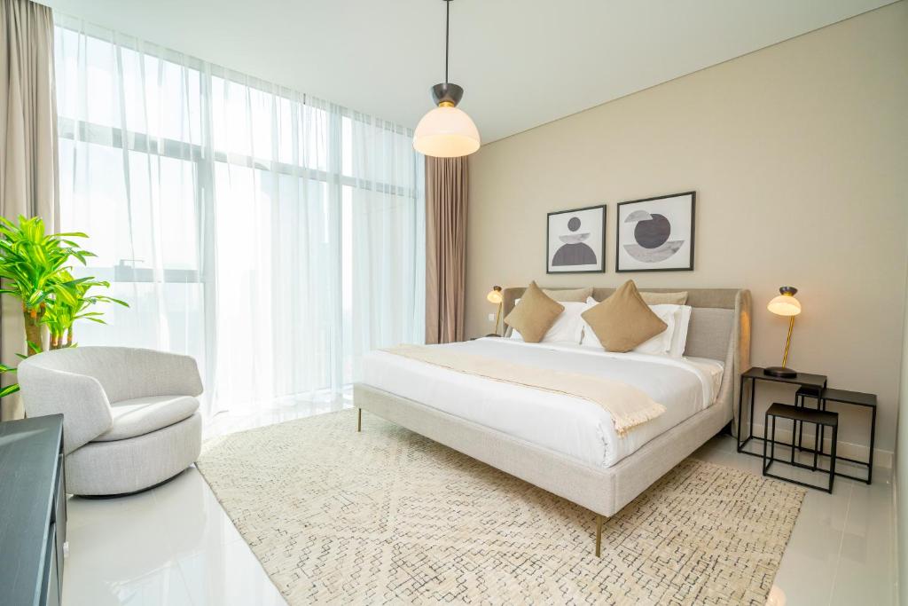 a bedroom with a large white bed and a chair at Fantastay Spacious 3 BDR plus maids with Burj Khalifa View in Dubai