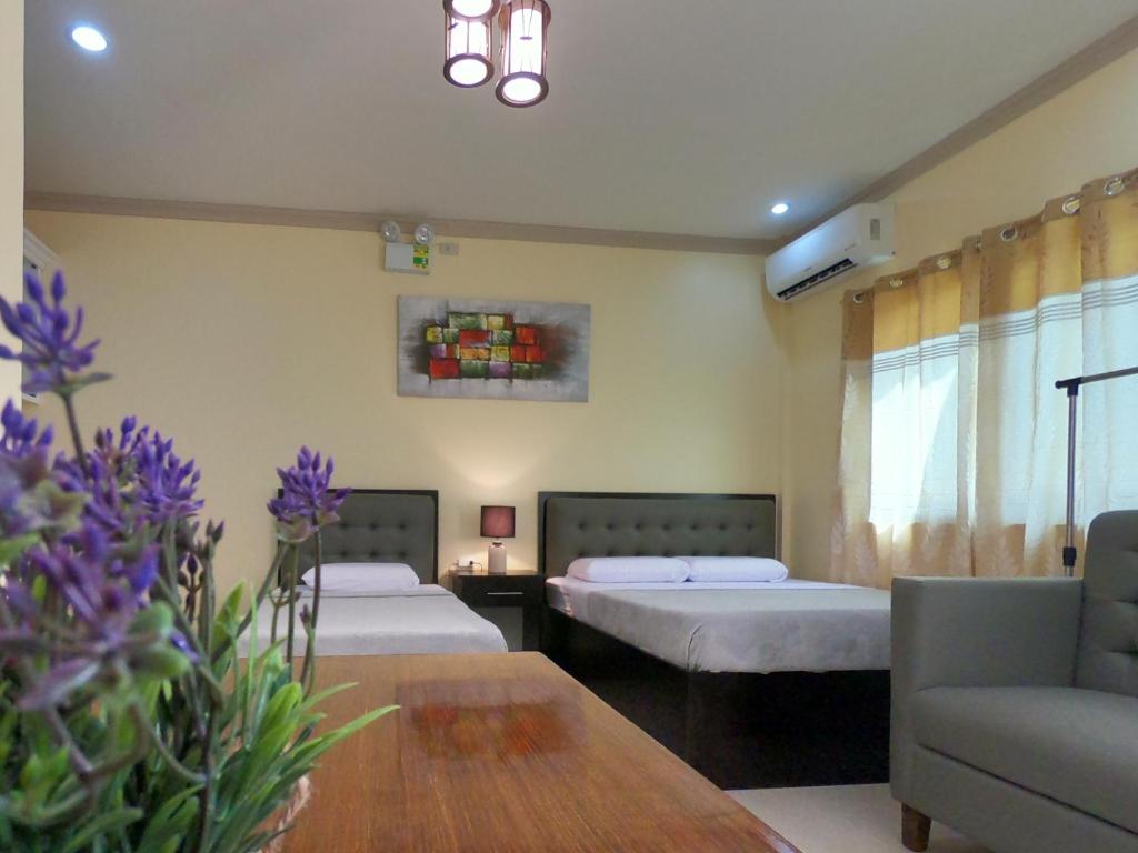 a room with two beds and a couch and a table at Mifaña Suites - Panglao Island in Dauis