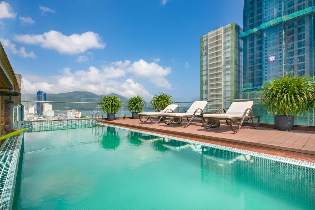 a swimming pool with two chairs and a building at Dolphin Hotel and Apartment in Da Nang