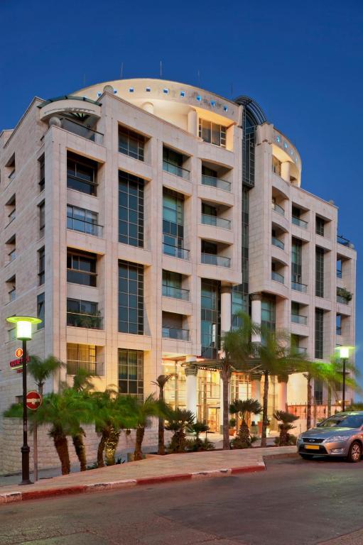 a large building with palm trees in front of it at Crowne Plaza Haifa by IHG in Haifa