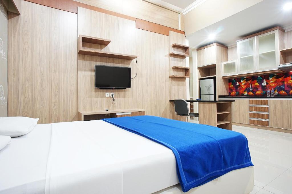 a bedroom with a bed and a tv and shelves at Hotel Bandung Permai in Bandung