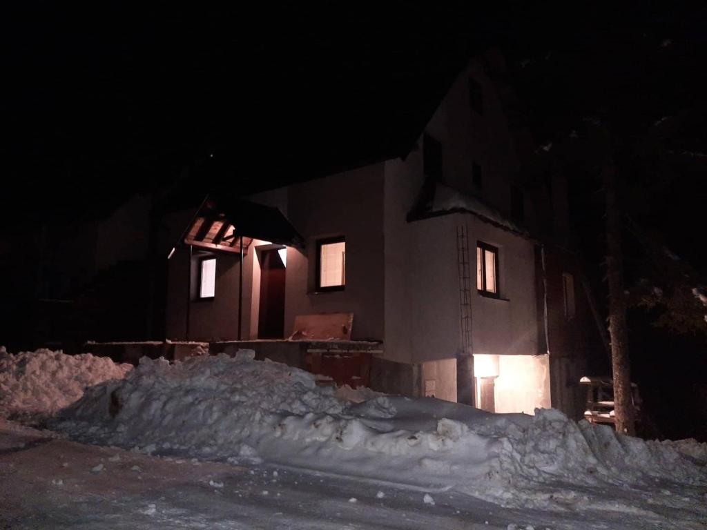 a house at night with a pile of snow at Jahorinska planinska kuća in Jahorina