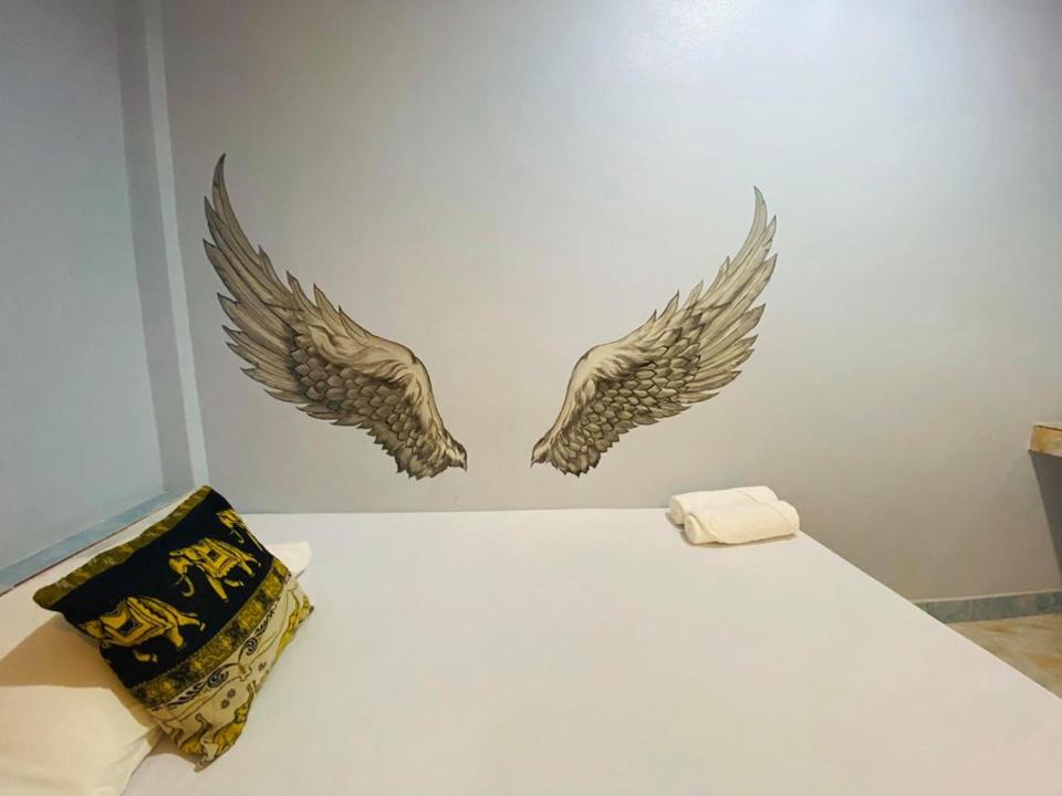 two wings on a wall next to a bed at Nong Or Blue House Resort in Sukhothai