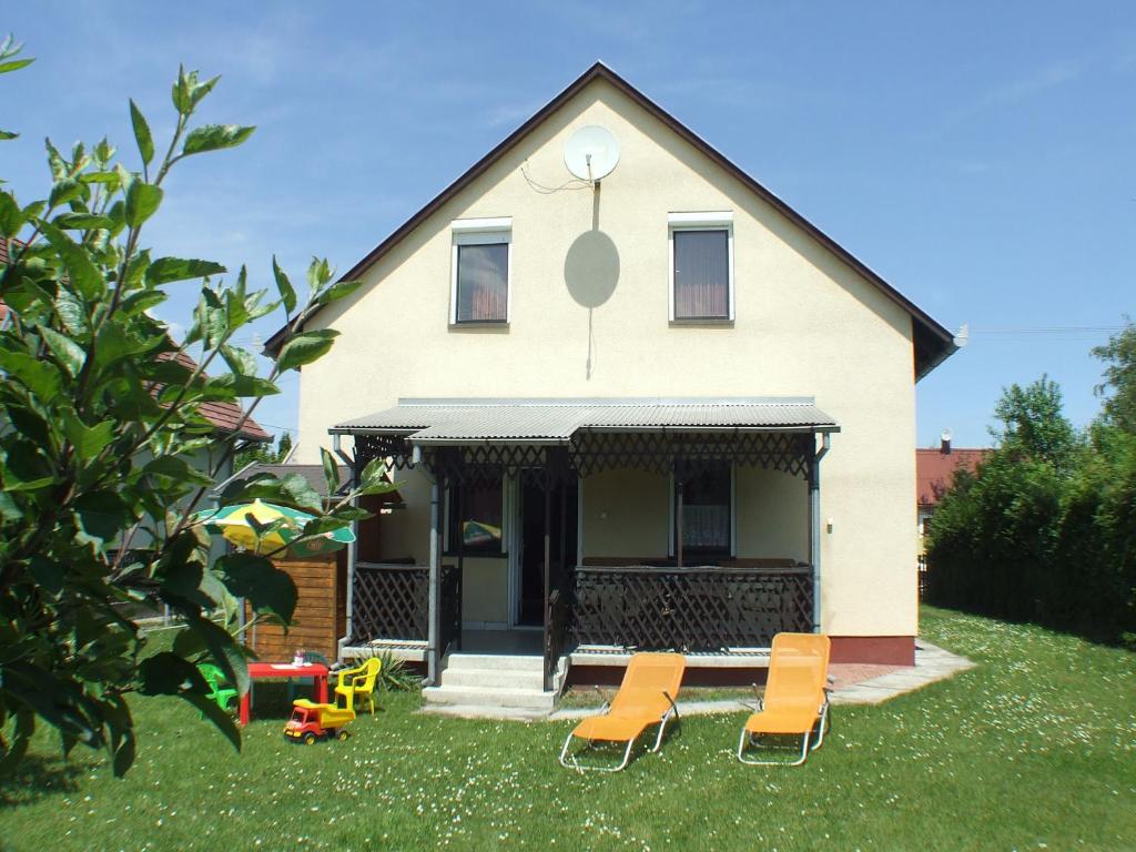 a house with chairs sitting in the yard at Katalin nyaraló in Balatonkeresztúr