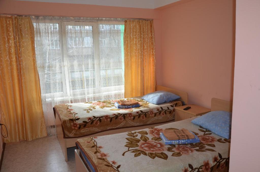 two beds in a small room with a window at Hotel Kezdesu in Almaty