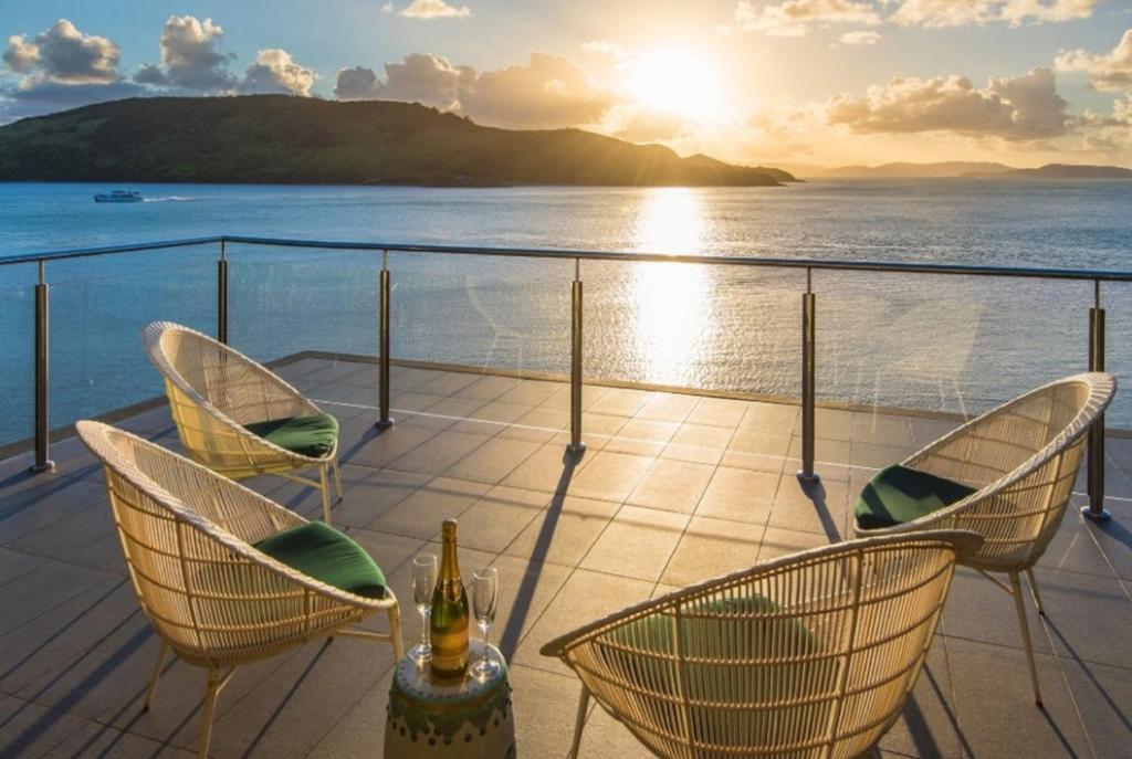 a deck with chairs and a bottle of wine at Yacht Club 19 Villa Bijou De Mer Ocean Front Private Pool 2 Buggies in Hamilton Island