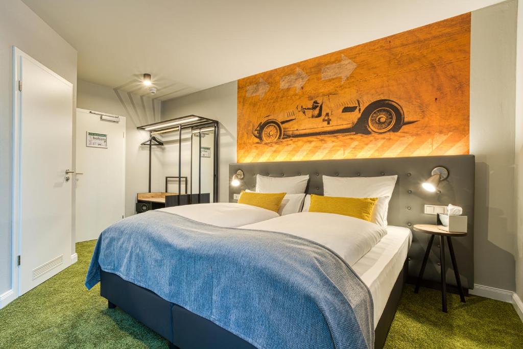 ein Schlafzimmer mit einem großen Bett und einem Gemälde eines Autos in der Unterkunft NYCE Hotel Ingolstadt in Ingolstadt