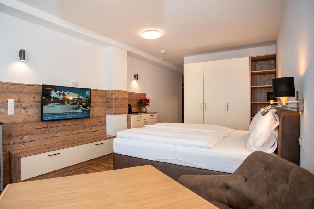 um quarto com uma cama e uma televisão na parede em Appartementhaus AURUM em Zell am See