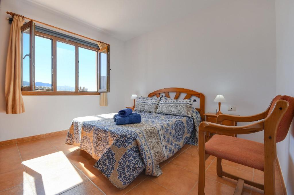 a bedroom with a bed and a chair and a window at Apartamentos Flor Seis in Caleta de Sebo
