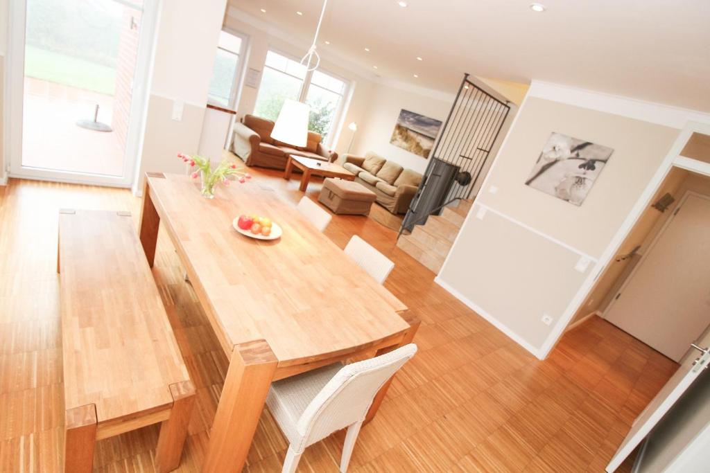 Logierhaus-Greetsiel 1 في غريتسيل: مطبخ وغرفة معيشة مع طاولة وكراسي خشبية