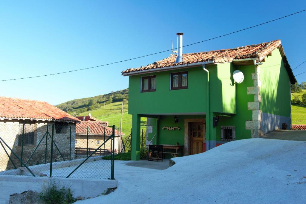 una casa verde con una colina al fondo en LA CASITA VERDE, en Onís