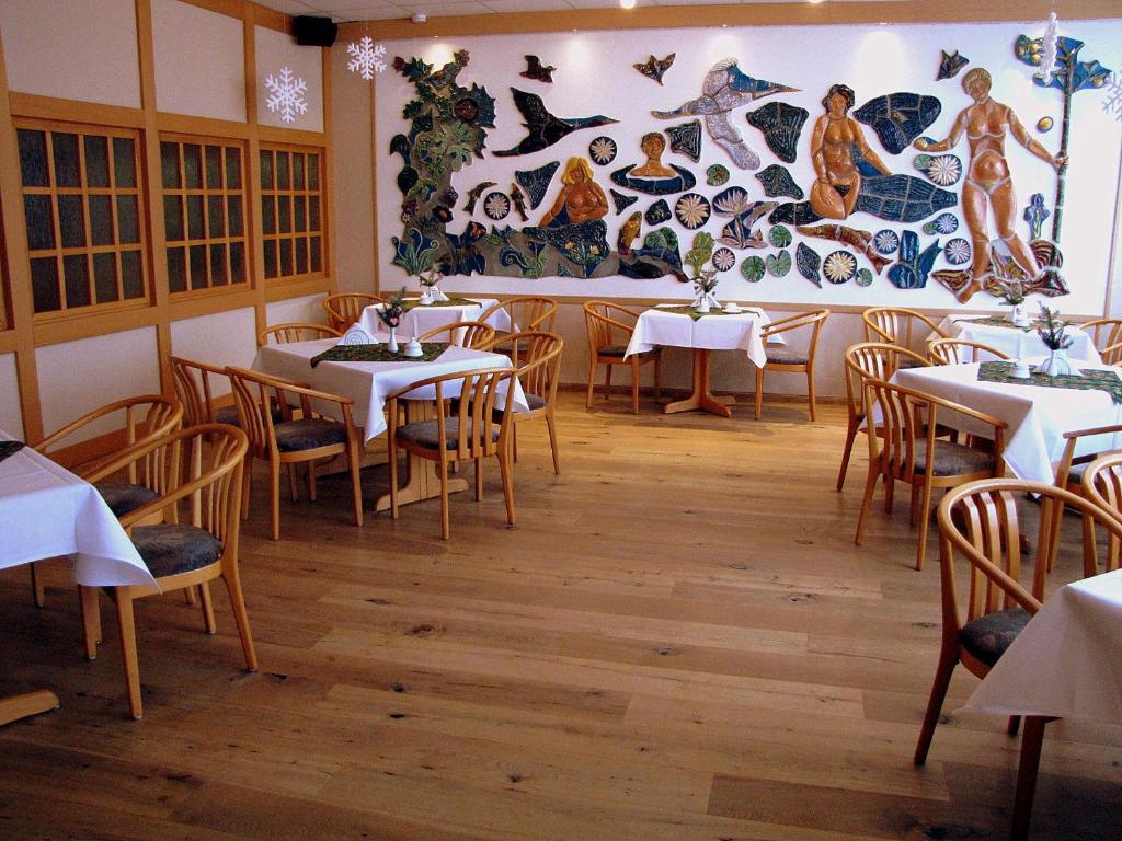 a restaurant with tables and chairs and a large mural at Hotel Stadt Wittstock in Wittstock