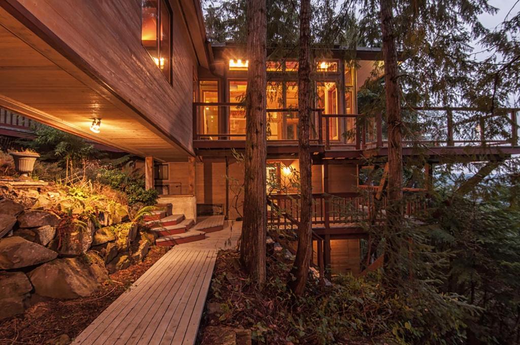 The Sanctuary Retreat & Spa في Salt Spring Island: منزل في الغابة مع سطح وأشجار