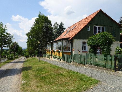 una pequeña casa verde y amarilla con una valla en Ferienwohnungen Weber en Friedrichsbrunn