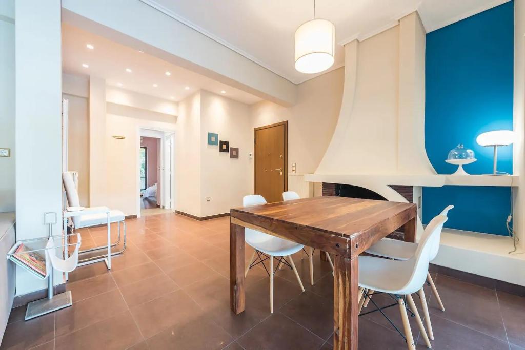 a dining room with a wooden table and white chairs at Glyfada Glass-Walled Designed Apt in Athens