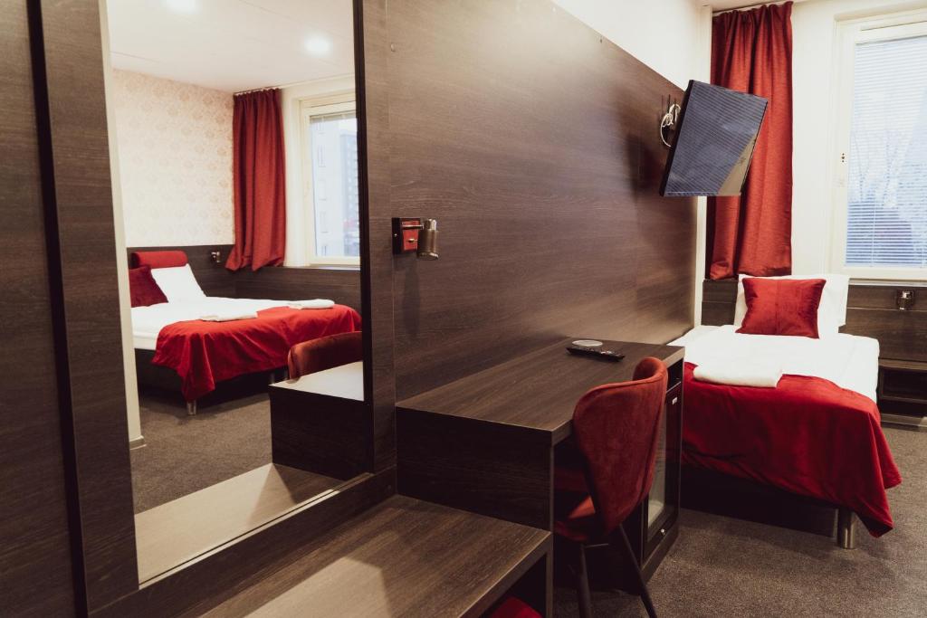 a room with two beds and a desk and a mirror at Liljeholmens Stadshotell in Stockholm