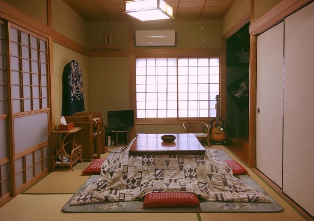 ein Zimmer mit einem Tisch in der Mitte eines Zimmers in der Unterkunft MaruHouse in Nachikatsuura