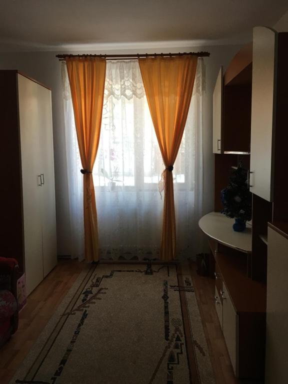 sala de estar con cortina naranja y ventana en Simona en Topliţa