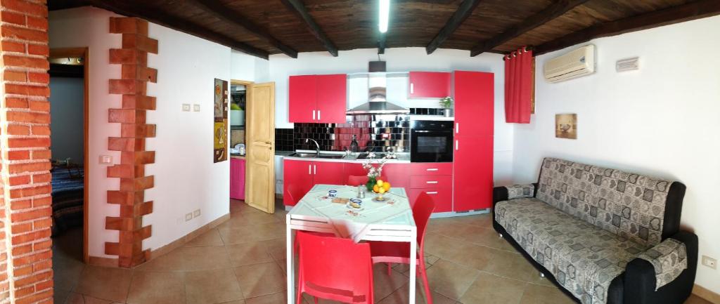 cocina con armarios rojos, mesa y sofá en Mansarda mare red, en Sciacca