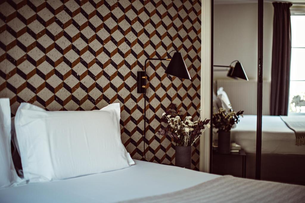 een slaapkamer met een wit bed en een muur bij Hotel Monsieur Helder in Parijs
