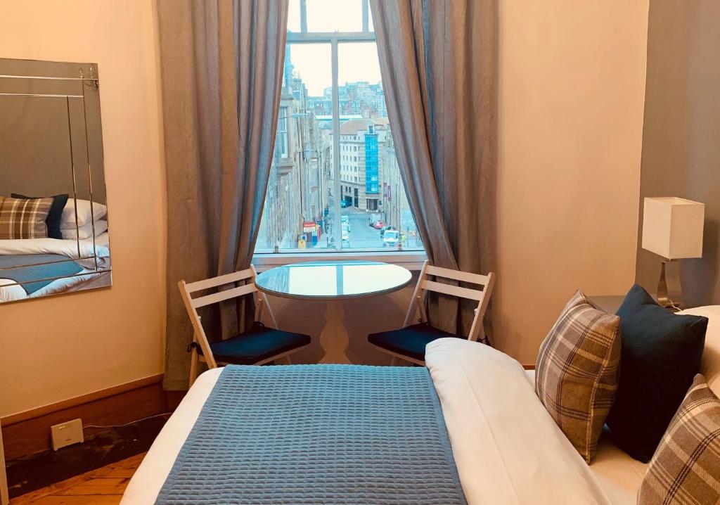 エディンバラにあるThe Royal Mile Residence by Reserve Apartmentsのベッド、テーブル、窓が備わる客室です。
