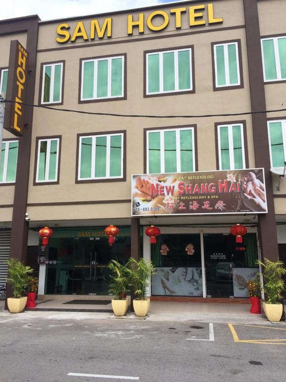 een gebouw met een nieuw shanghai hotel met planten voor de deur bij Sam Hotel in Sitiawan