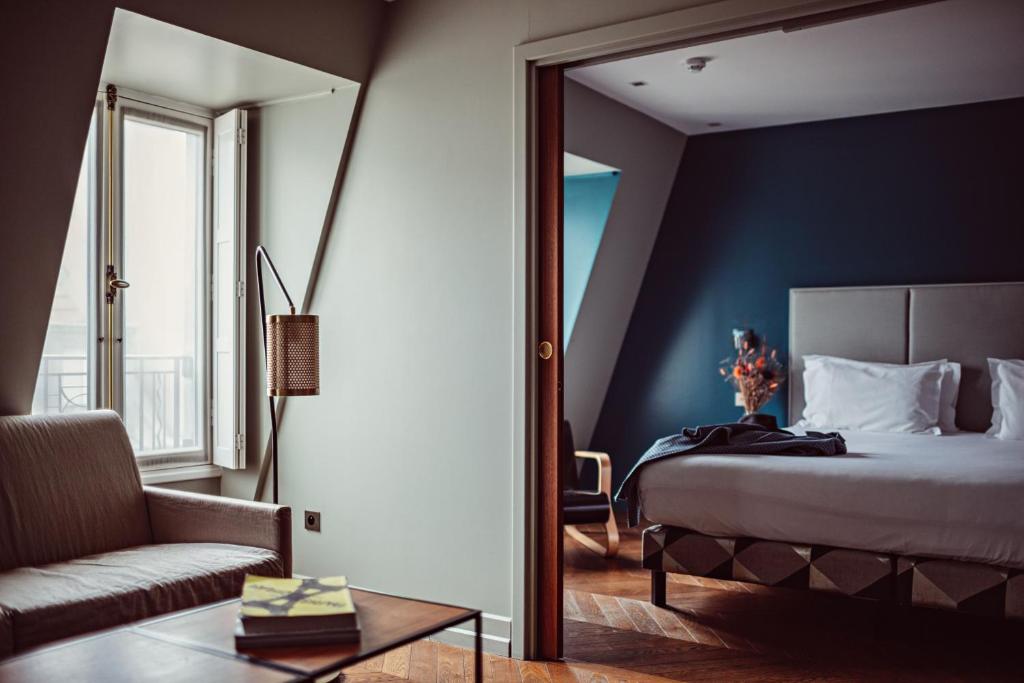 a bedroom with a bed and a couch and a mirror at Monsieur Cadet Hotel & Spa in Paris