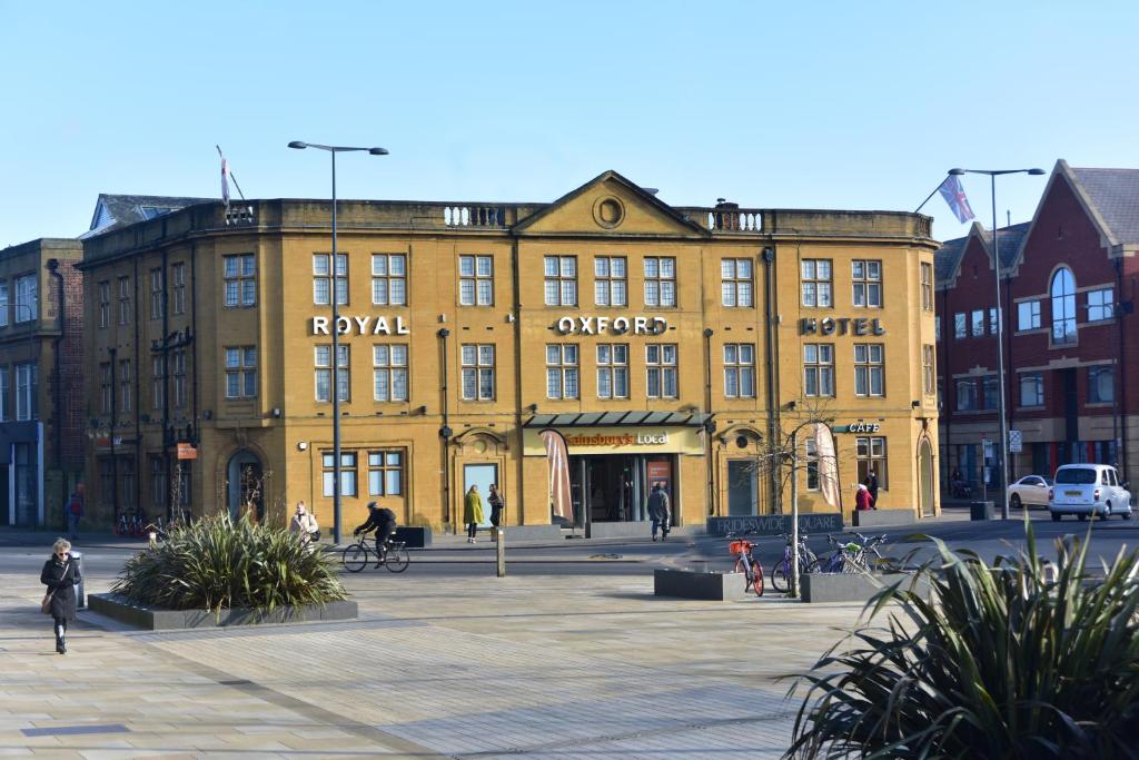 a large yellow building with people walking in front of it at Royal Oxford Hotel in Oxford