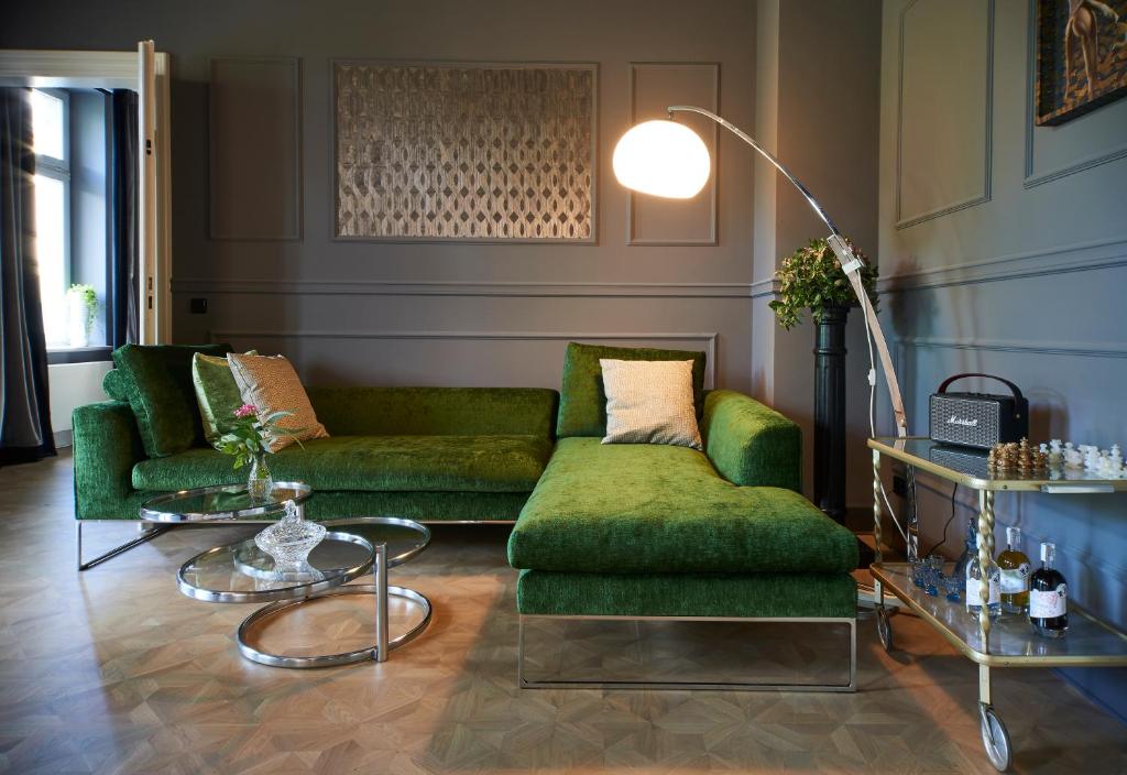 a living room with two green couches and tables at Cora Apartments in Leipzig