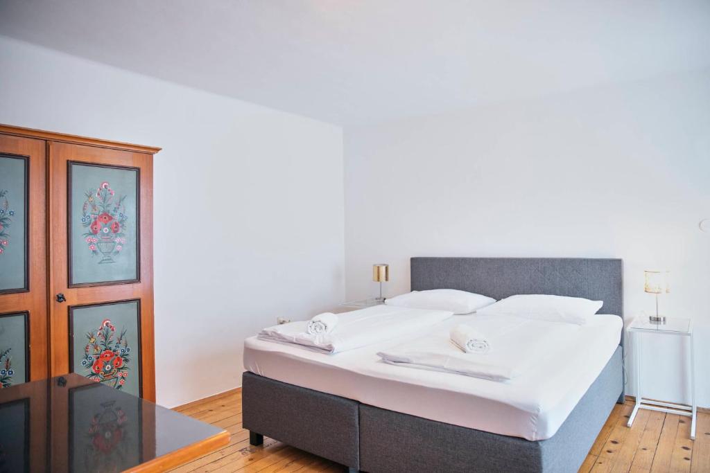 ザルツブルクにあるガストホフ ヴァストルヴァートのベッドルーム(白いシーツを使用した大型ベッド1台付)