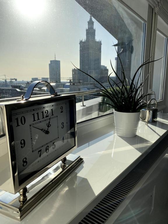 a clock sitting on a window sill next to a plant at Leo Apartment in Warsaw
