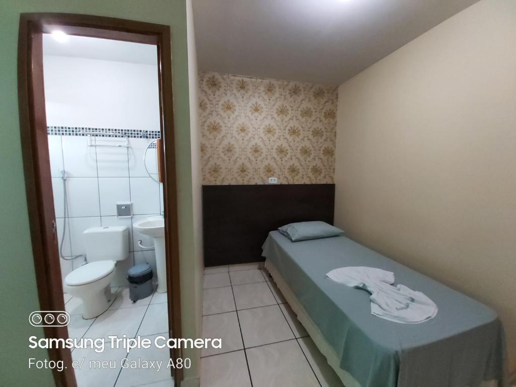 a small bedroom with a bed and a toilet at Araguaia Hotel in Bom Jesus