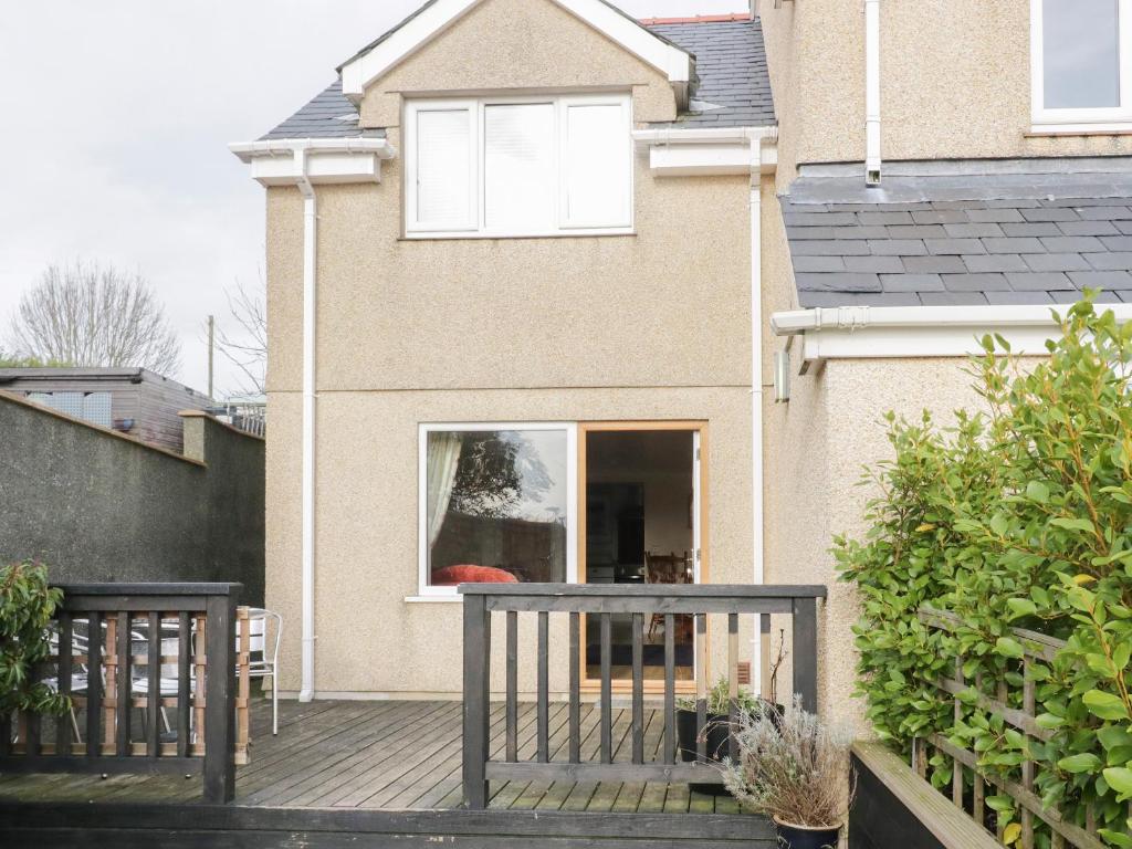 a house with a wooden deck with a window at Bryn Y Don Cottage in Benllech