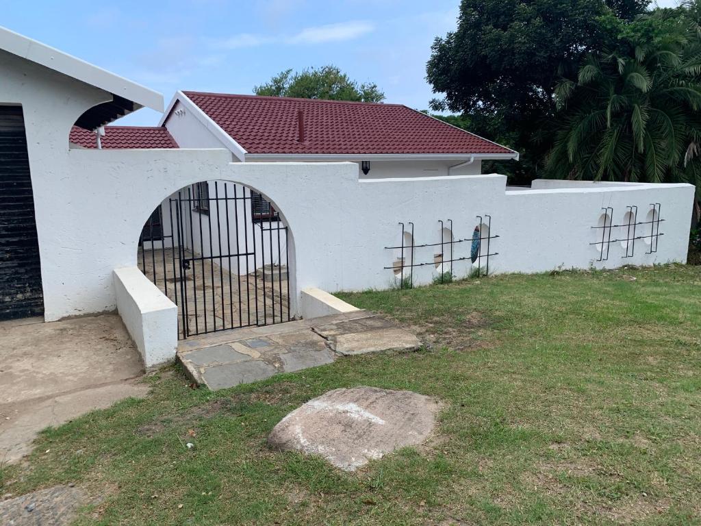 a white house with a gate in a yard at White House lodge in Scotburgh in Scottburgh