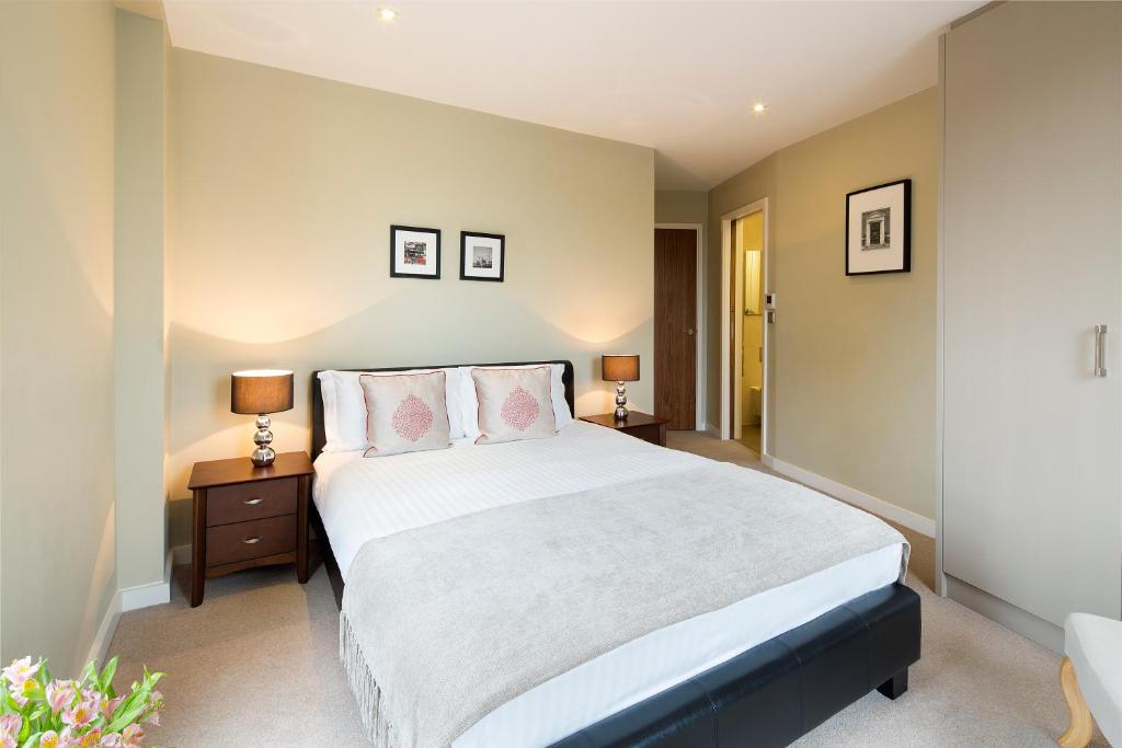 a bedroom with a large white bed with two lamps at Victoria One in London