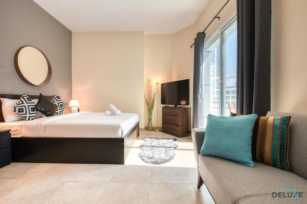 a bedroom with a bed and a tv and a couch at Spotless Studio in Dubai Gate 2 JLT by Deluxe Holiday Homes in Dubai