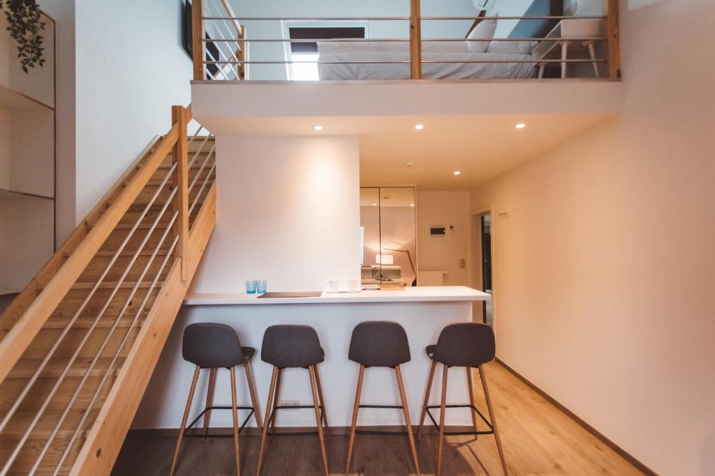 a kitchen with three stools at a bar in a loft at HDC Nivelles Grand-Place in Nivelles