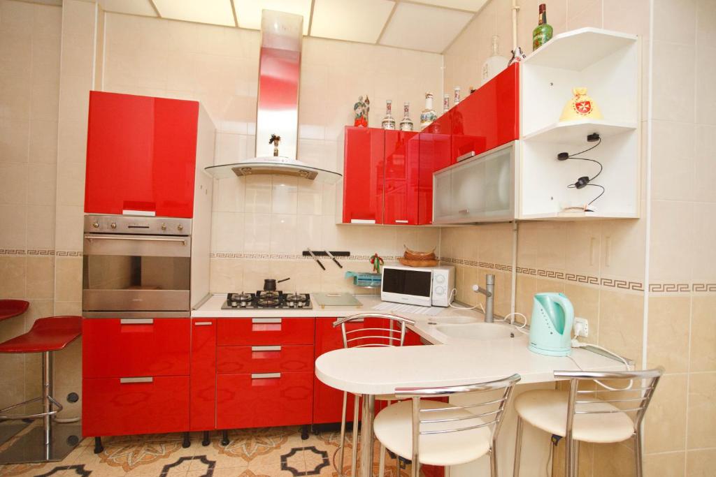 une cuisine avec des placards rouges et une table blanche dans l'établissement Central apartments Lviv, à Lviv