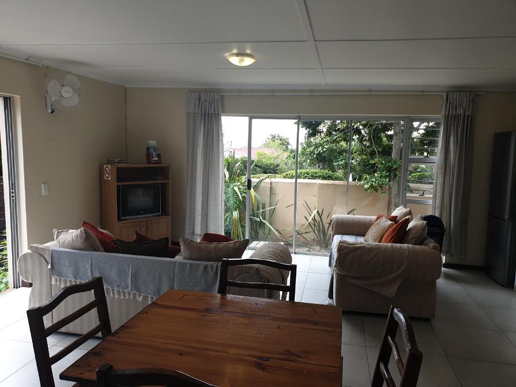 ein Wohnzimmer mit einem Sofa, Stühlen und einem Tisch in der Unterkunft Amakaya Backpackers Travellers Accommodation in Plettenberg Bay